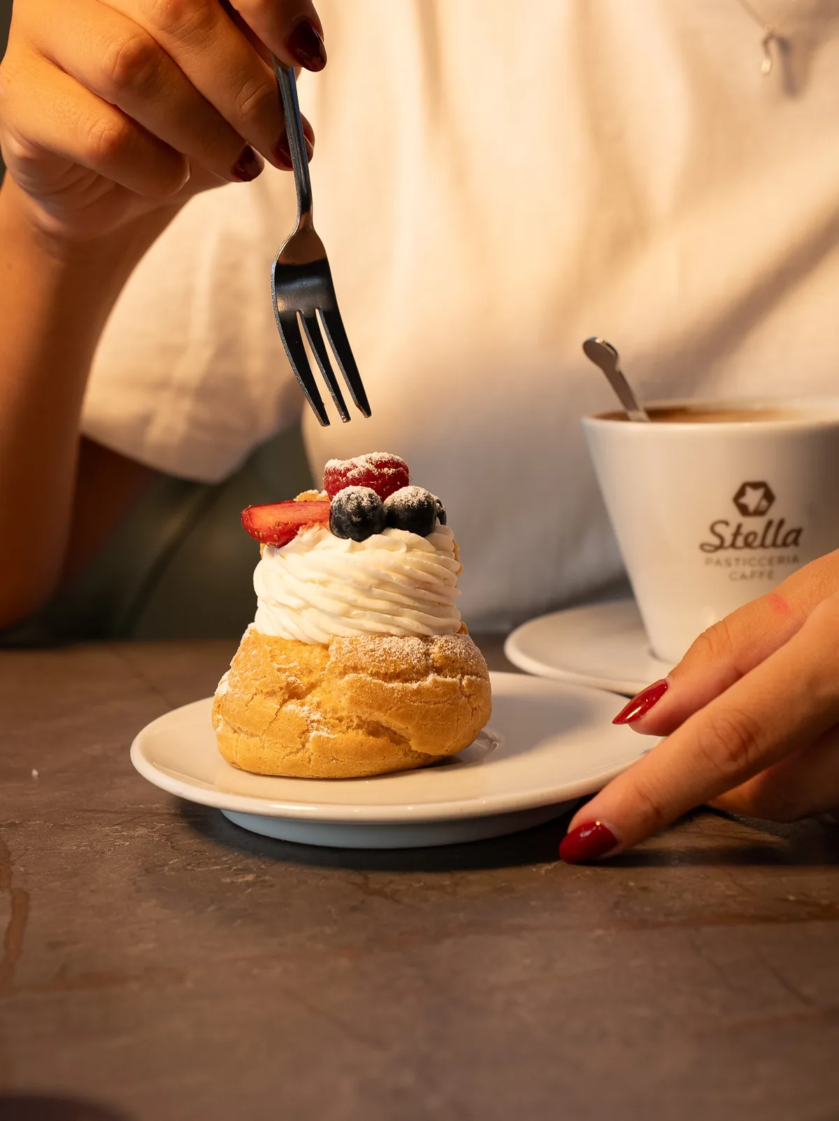 Bignè con panna e frutti di bosco accanto a una tazza di caffè Stella, Pasticceria Stella Lucca